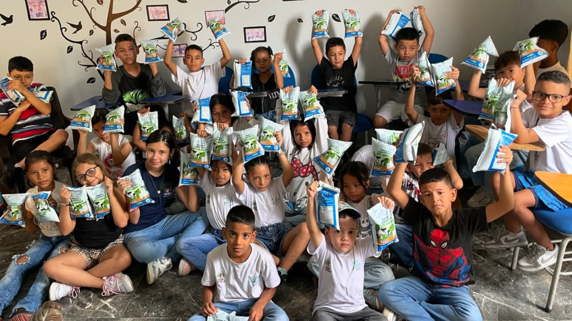 Niños y niñas de FUNISER en el aula frente al mural del árbol institucional durante una jornada nutricional y pedagógica